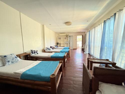 a row of four beds in a room with windows at Blue Villa - Entire House with Private Pool in Panglao Island