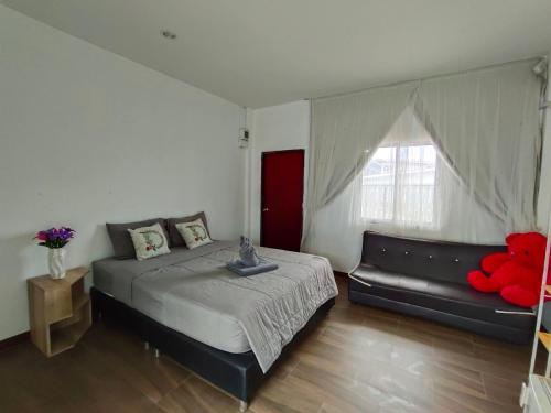 a bedroom with a bed and a couch and a window at บ้าน พัก ดี เกาะล้าน Ban Phak D Koh Larn in Ko Larn