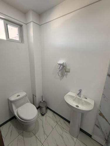 a white bathroom with a toilet and a sink at MarDani Guesthouse & Car Rental - FREE SJO Airport Shuttle in Alajuela