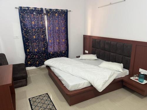 a bedroom with a bed with a wooden headboard at Hotel Dubeyinn in Katra