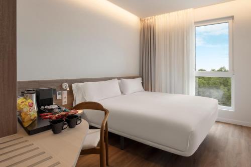 a hotel room with a large white bed and a desk at B&B HOTEL Madrid Vallecas Ensanche in Madrid