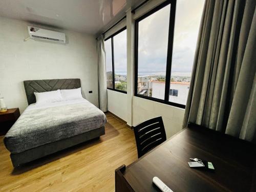 a bedroom with a bed and a table and windows at Hospedaje Zerimar in Puerto Baquerizo Moreno
