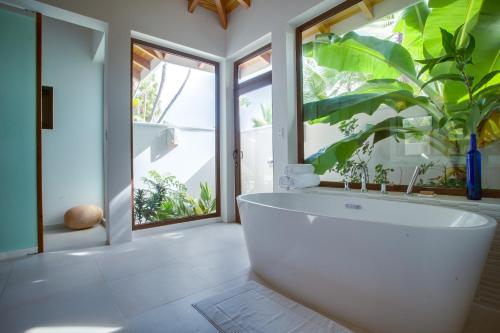 a white bath tub in a bathroom with a plant at Naïa Resort and Spa in Placencia Village