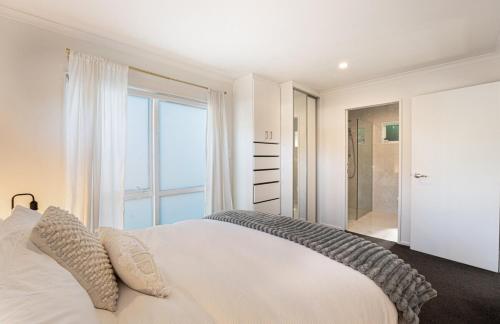 a bedroom with a white bed and a large window at Studio 17 Private Standalone Studio in Greenhithe North Shore in Auckland