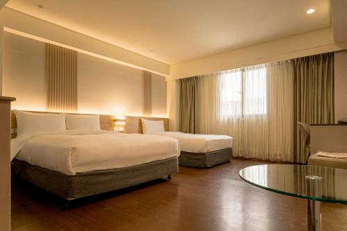 a hotel room with two beds and a glass table at VIP Hotel in Taipei