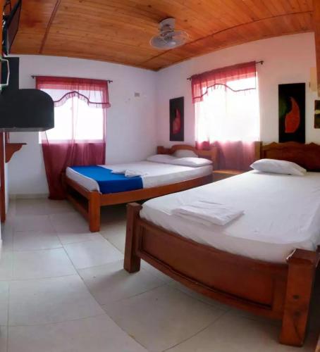 two beds in a room with two windows at Alojamiento PLAYA DORADA Coveñas in Coveñas