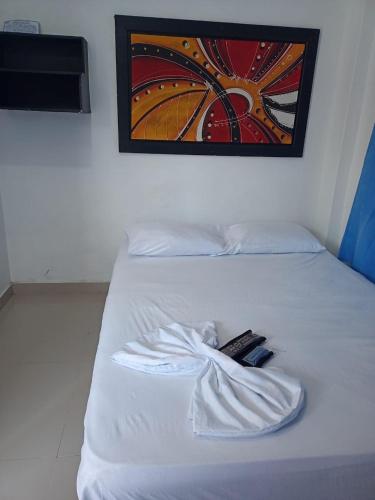 a white bed with a remote control on it at Alojamiento PLAYA DORADA Coveñas in Coveñas