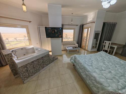 a bathroom with a tub and a bed and a television at Avrio Red Sea in Hurghada