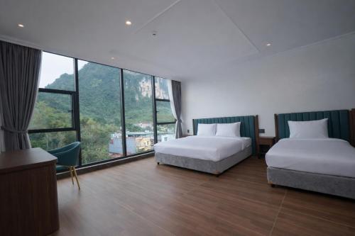two beds in a room with large windows at Ha Giang Numa Hotel in Ha Giang