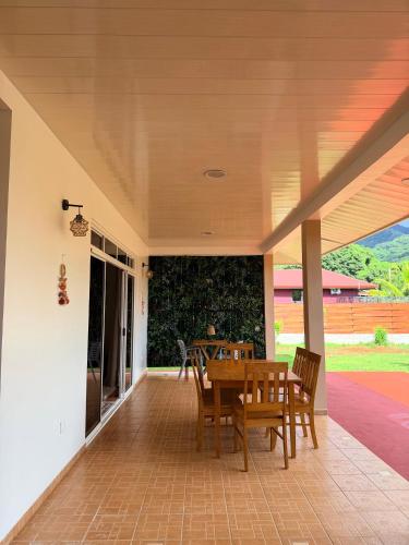 a porch with a wooden table and chairs on it at Fare Hinenao in Tevaitoa