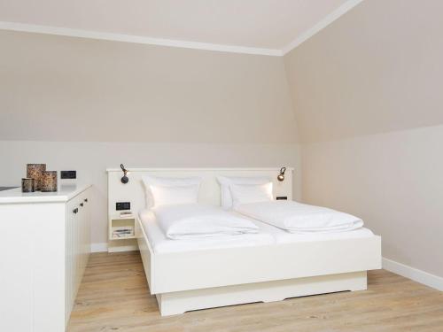 a white bedroom with a white bed with white pillows at Kliffsand-73 in Kampen