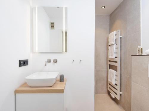 a white bathroom with a sink and a mirror at Kliffsand-73 in Kampen