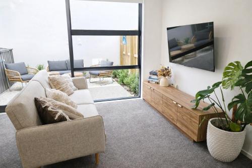 a living room with a couch and a tv at Luxury 2 Bed 2 Bath Townhouse Central Christchurch in Christchurch