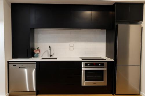 a kitchen with black cabinets and stainless steel appliances at Luxury 2 Bed 2 Bath Townhouse Central Christchurch in Christchurch