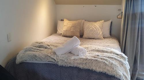 a bed with a white blanket and pillows on it at Remarkable studio,close to airport in Queenstown