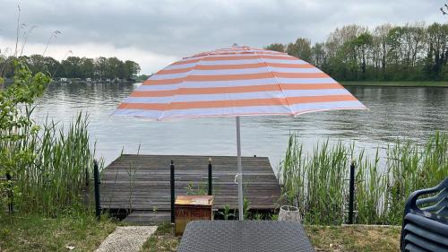 an umbrella sitting on a dock next to a body of water at Twee slaapkamer stacaravan met vissteiger in Hengelo