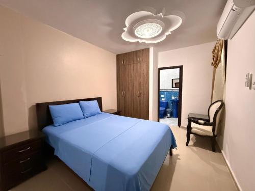 a bedroom with a blue bed and a chandelier at Kiosco Azul - Apartamento amoblado cerca al mar in Ríohacha
