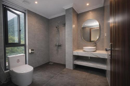 a bathroom with a toilet and a sink and a mirror at Ha Giang Numa Hotel in Ha Giang