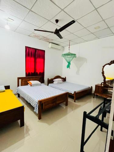 two beds in a room with red curtains at Pudam Cottege in Kataragama