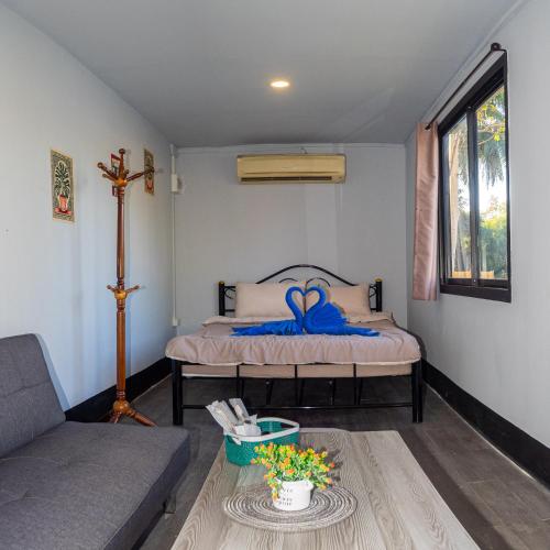 a bedroom with a bed with a blue bow on it at Lakeside Cargo in Yellow - A Cozy Container Stay in San Pa Tong