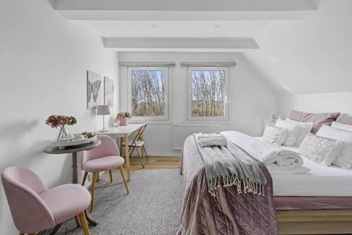 a bedroom with a bed and two pink chairs at Hambo Stay in Staffanstorp