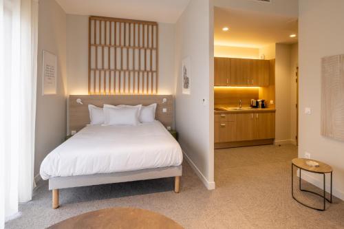 a bedroom with a white bed and a kitchen at Le PIC in Clermont-Ferrand