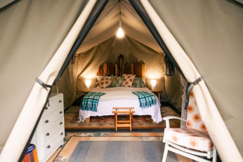a bedroom in a tent with a bed and a chair at HighlandsView in Swellendam