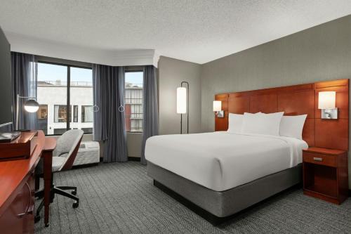 a hotel room with a large bed and a desk and a desk at Courtyard by Marriott Fishermans Wharf in San Francisco