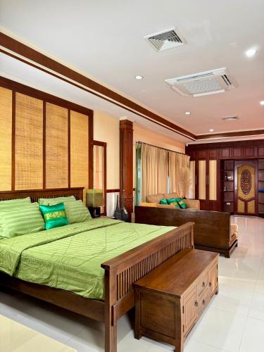 a bedroom with a bed with green sheets and a bench at Baan Katthaliya in Hua Hin