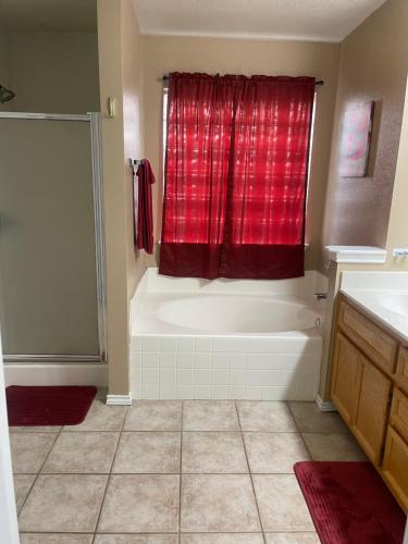 a bathroom with a tub and a red shower curtain at Kindness Dwells in Killeen