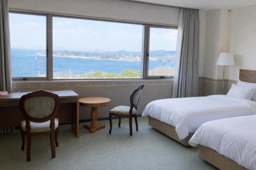 a hotel room with two beds and a desk and a window at 天海の城 in Saikai