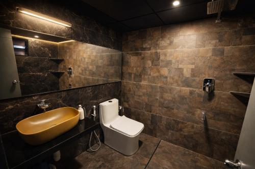 a bathroom with a toilet and a sink and a mirror at TAM BoSa Beach Retreat in Kalyānpur