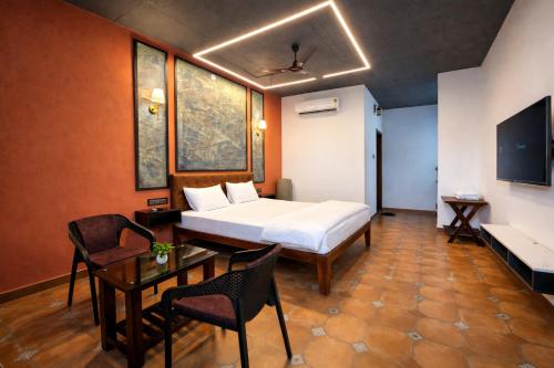 a hotel room with a bed and a table and chairs at TAM BoSa Beach Retreat in Kalyānpur