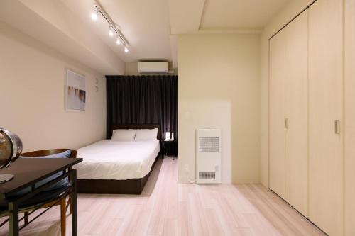 a bedroom with a bed and a desk and a table at Mondomio 207 in Sapporo