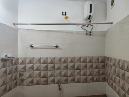 a bathroom with a shower with a tiled wall at Staysafe in Kattakkada