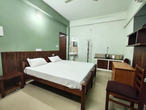 a bedroom with a large white bed and a bathroom at Staysafe in Kattakkada