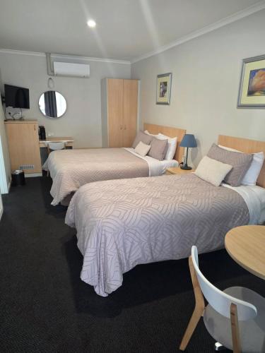 a hotel room with two beds and a table at Nebula Motel in Cooma