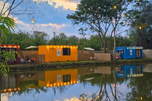 a group of mobile homes next to a body of water at Lakeside Cargo in Yellow - A Cozy Container Stay in San Pa Tong