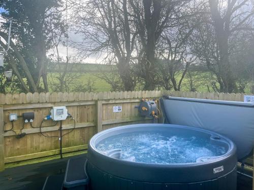 a hot tub in a backyard with a wooden fence at Bluebell Lodge - Uk51382 in Wigton