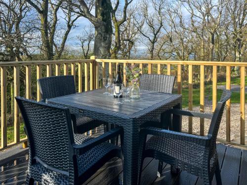 a black table with chairs and a bottle and glasses at Herdwick Lodge - Uk51383 in Westward