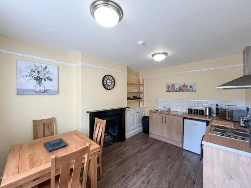 a kitchen and dining room with a table and a fireplace at Albert Cottage in Llandudno