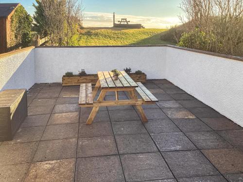 a picnic table and a bench on a patio at Wee Shore Walk in Balintore