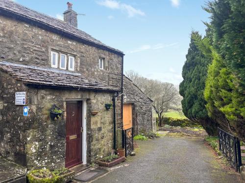 an old stone house with a red door on a street at Blindbeck Holiday Cottage in Settle