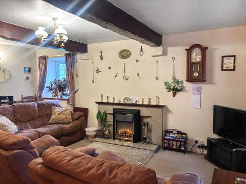 a living room with a couch and a fireplace at Blindbeck Holiday Cottage in Settle