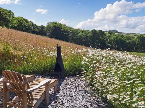 two chairs and a wine bottle in a field of flowers at Pip's Hut in Bideford
