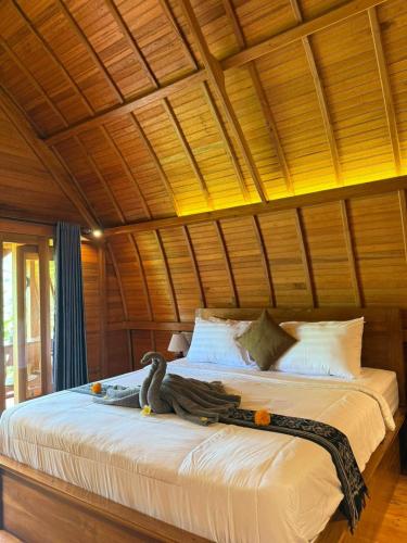 a bedroom with a large bed with a wooden ceiling at Lumbung Intan in Sidemen