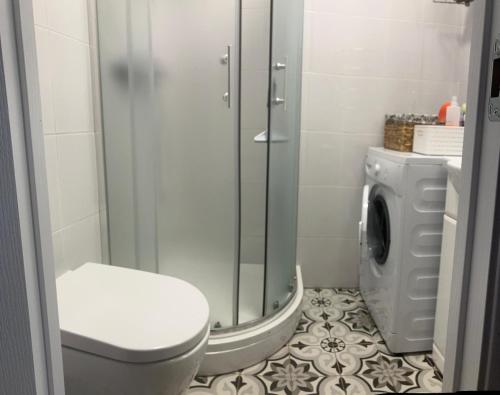 a bathroom with a shower and a toilet and a washing machine at Kovarnu street apartment in Cēsis