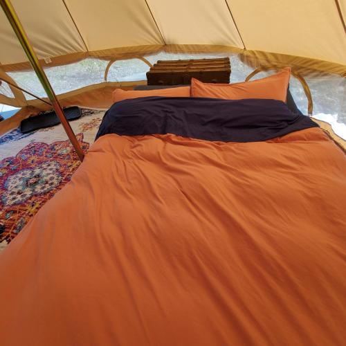 a bed in a tent with an orange blanket at Alaskan Glamping in Anchorage