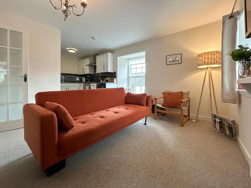 a living room with an orange couch in a room at Sea View Apartment in Anstruther