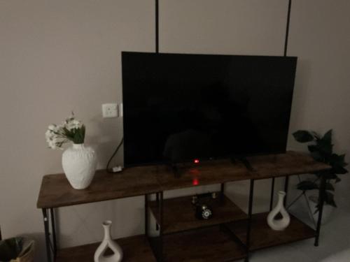 a television on a wooden table with a vase of flowers at روڤان in Hafr Al-Batin